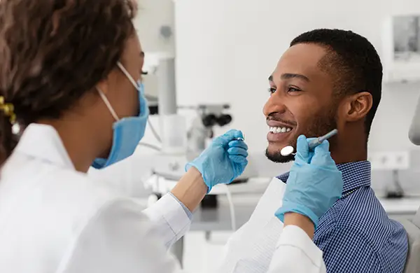 A dentist performing a dental check-up on a smiling male patient at Radiance Dental in West Chester, PA